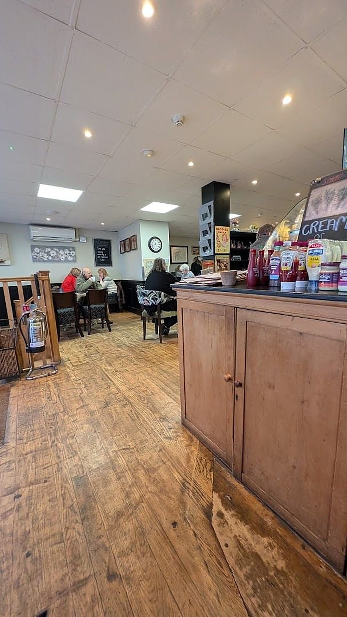 Inside Brogans: bare wooden floorboards, a wooden counter on the right and tables along the far wall under bright ceiling lights